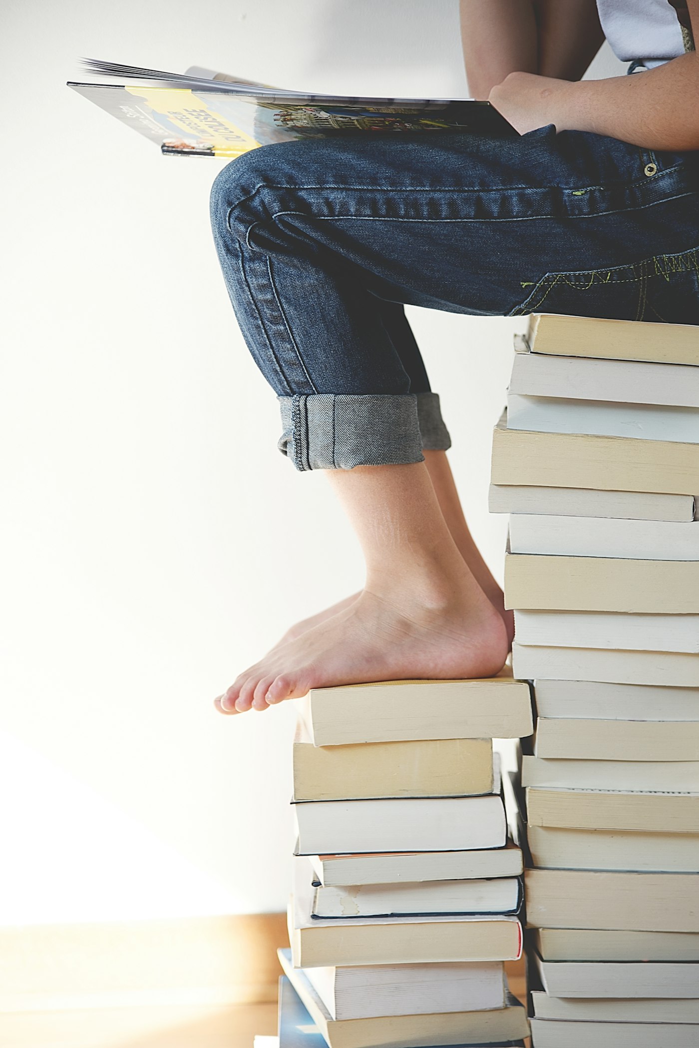 Reader seated on a stack of books.
